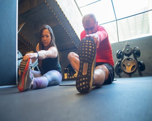 Instructor assisting a gym member with their stretching routine